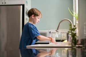 A boy washing his hands with soap and water to be safe from COVID-19