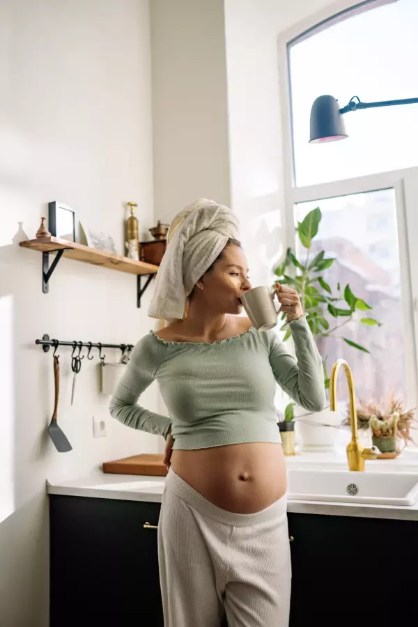 Seorang ibu hamil yang sedang menjaga kelembapan kulit dengan meminum air